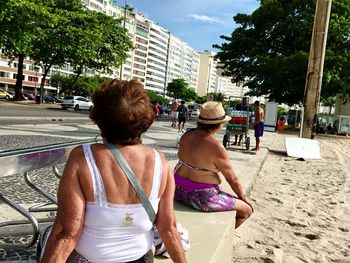 Rear view of people sitting on street in city