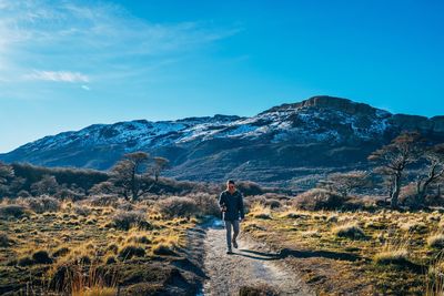 Rear view of man walking on mountain against sky