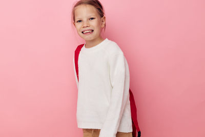 Portrait of smiling girl against pink background