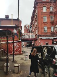 Rear view of woman standing on street against buildings