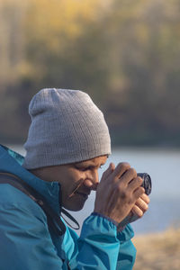 Portrait of traveler man at lake in autumn taking a photo with the digital camera