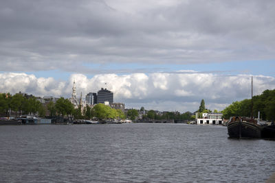 Scenic view of river by buildings against sky