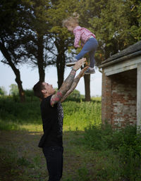 Father catching cute daughter while standing on field