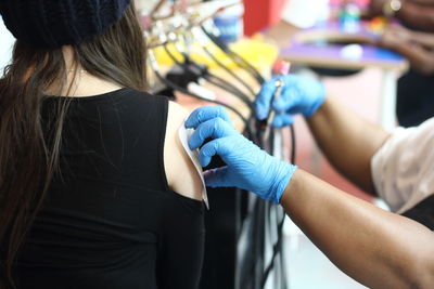 Cropped hands of artist making tattoo on female customer