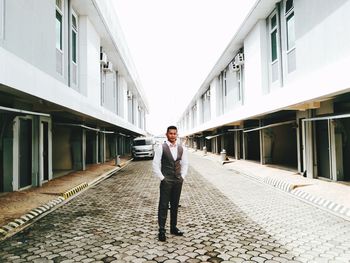 Full length portrait of young man standing against building