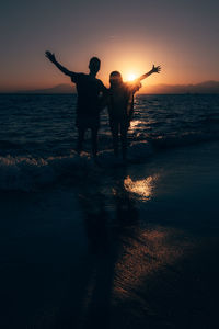 Rear view of man with arms outstretched standing at beach