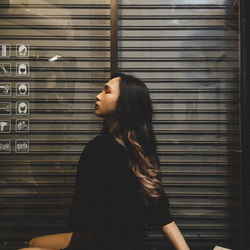 Side view of woman looking through window