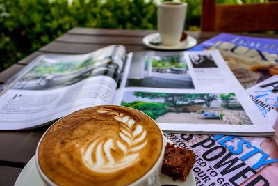 High angle view of cappuccino and magazines on table in yard