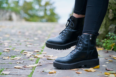 Close-up of the boots worn by a woman in military style in black with a stone floor background