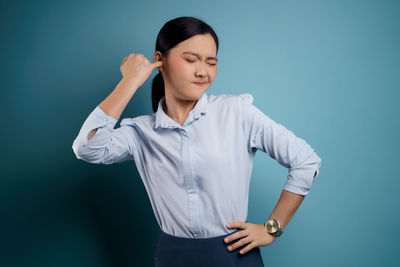 Young woman standing against blue background