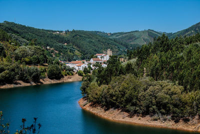 Scenic view of river and mountains against clear blue sky