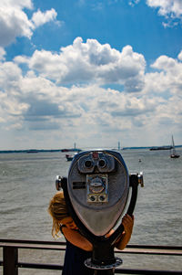 Close-up of coin-operated binoculars by sea against sky