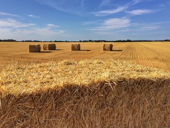 Hay bales on field against sky