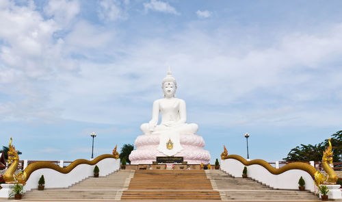 Statues of building against cloudy sky