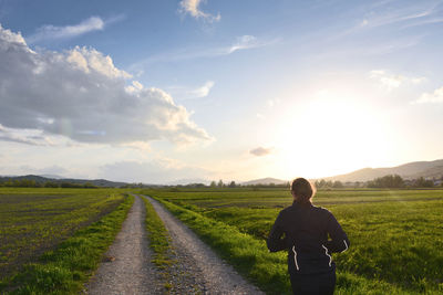Rear view of woman standing on field against sky