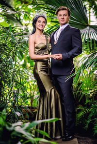 Portrait of smiling young couple standing against trees