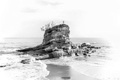 Rock formation on beach against sky