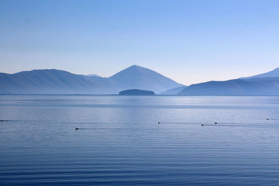 Scenic view of lake and mountains against clear blue sky