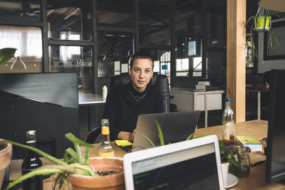 Portrait of businesswoman working over laptop at workplace