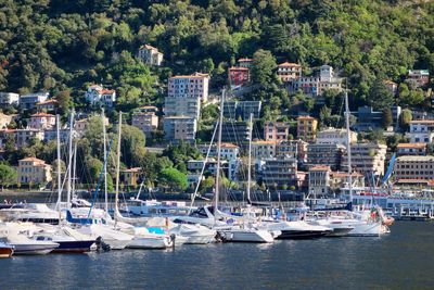 Boats moored in harbor against buildings in city