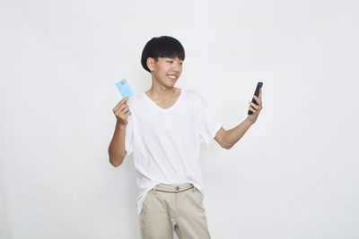 Young woman using mobile phone against white background