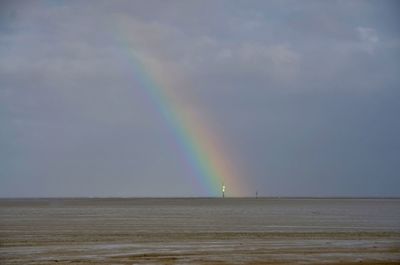 Scenic view of rainbow over sea against sky