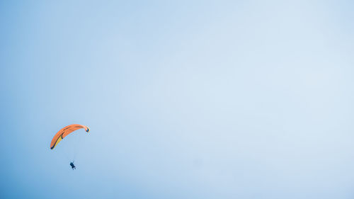 Low angle view of person paragliding against clear sky