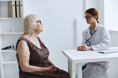 Doctor consulting senior woman at hospital
