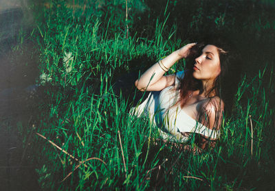 Woman lying amidst grass on land