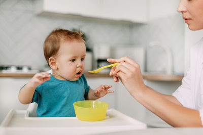 Mother feeding boy at home