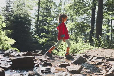 Child crossing mountain stream. little girl walking in mountains, spending summer vacations