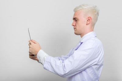 Side view of man holding camera over white background