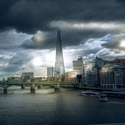 City at waterfront against cloudy sky