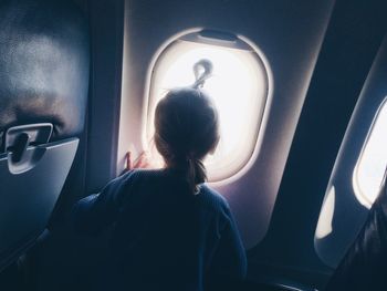 Rear view of woman sitting in airplane