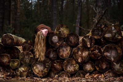 Young woman lying on wooden logs in forest
