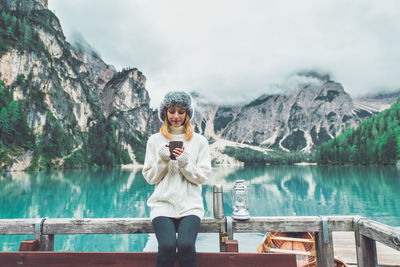 Full length of man sitting on lake against mountains