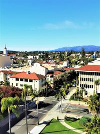 High angle view of road by buildings against blue sky