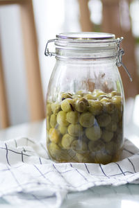 Close-up of green tomatoes in a glass jar on table