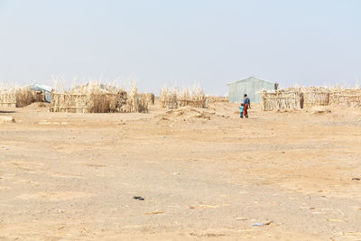 Man walking on field against clear sky