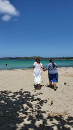 Rear view of women on beach against sky