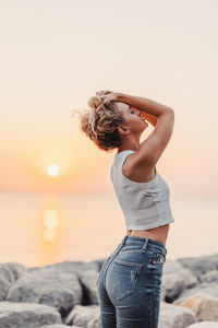 Woman standing on beach against sky during sunset