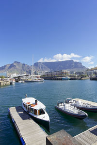 Boats moored in calm sea against blue sky