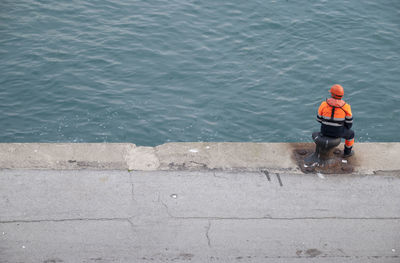 Rear view of manual worker sitting on promenade