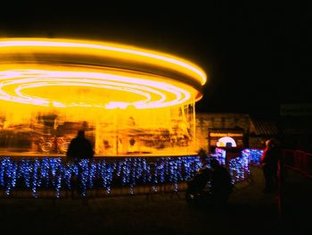 Group of people at amusement park ride at night