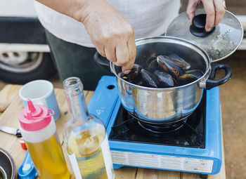 Senior woman cooking mussels in camping gas on in her van