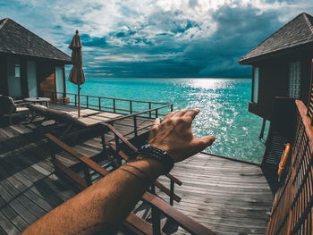 Low angle view of hand by sea against sky