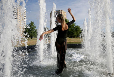 Rear view of woman standing in fountain