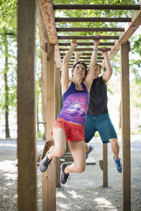 Determined couple hanging on monkey bars at outdoor gym