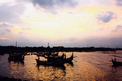 Silhouette boats in sea against sky during sunset