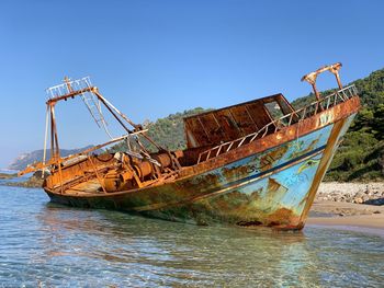 Abandoned ship in sea against clear sky